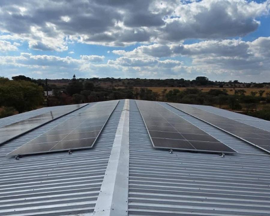 Panels on a long corrugated roof under cloudy sky