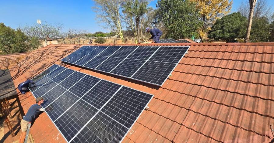 Installers placing solar panels on a clay-tile roof